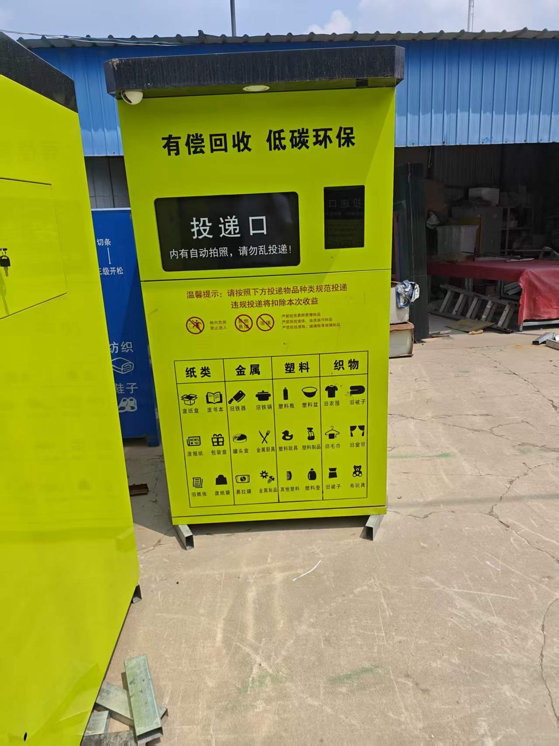 智能回收箱户外实景，箱体标注有偿回收低碳环保与投递口、纸类金属塑料织物投放指南